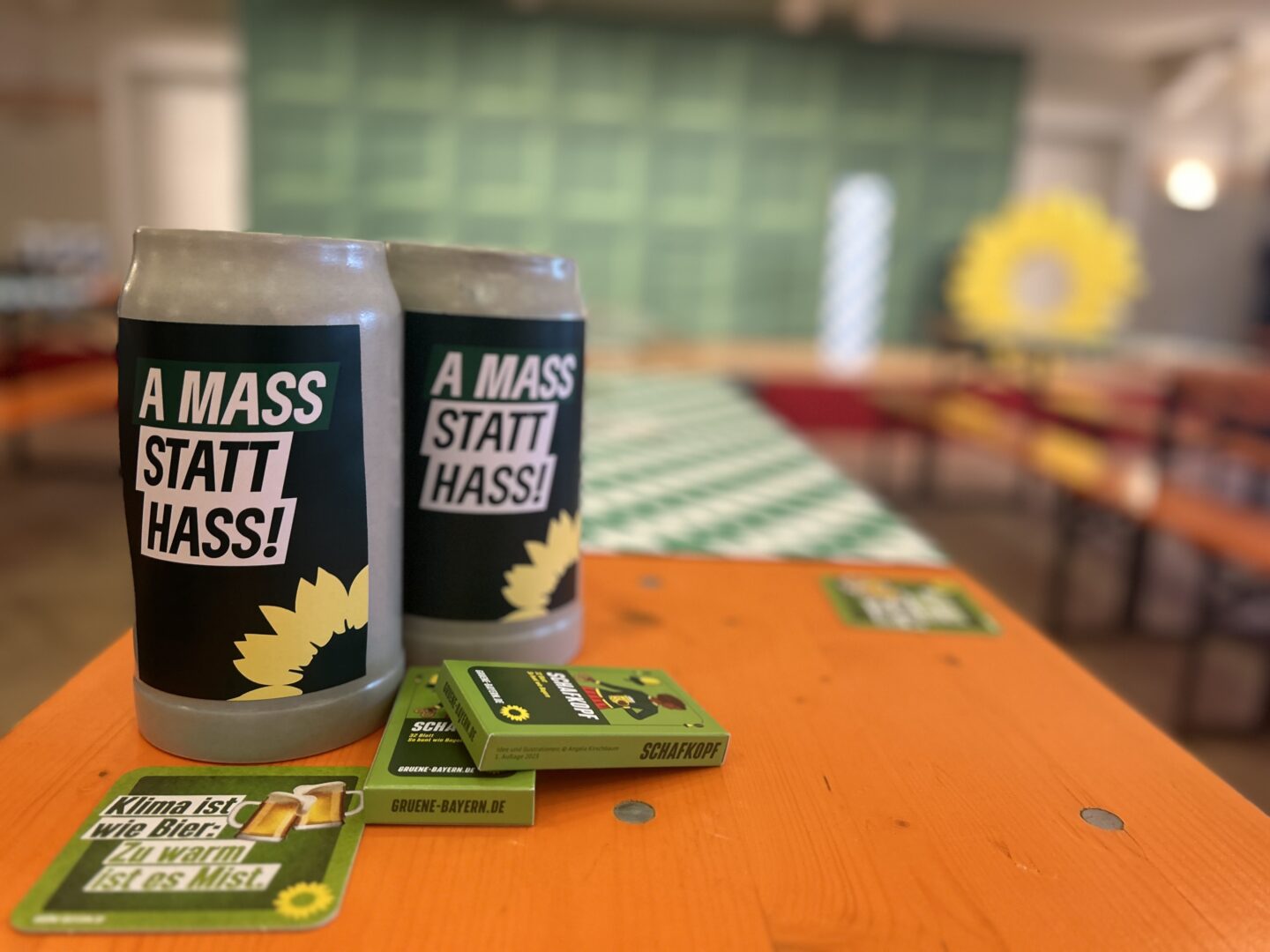 Bierkrug mit dem Aufdruck "A Mass statt Hass" – das Motto des Aschermittwochs der GRÜNEN Bayern 2024. Das Bild zeigt den Bernlochner Stadtsaal in Landshut, in dem der Politische Aschermittwoch der GRÜNEN traditionell stattfindet.