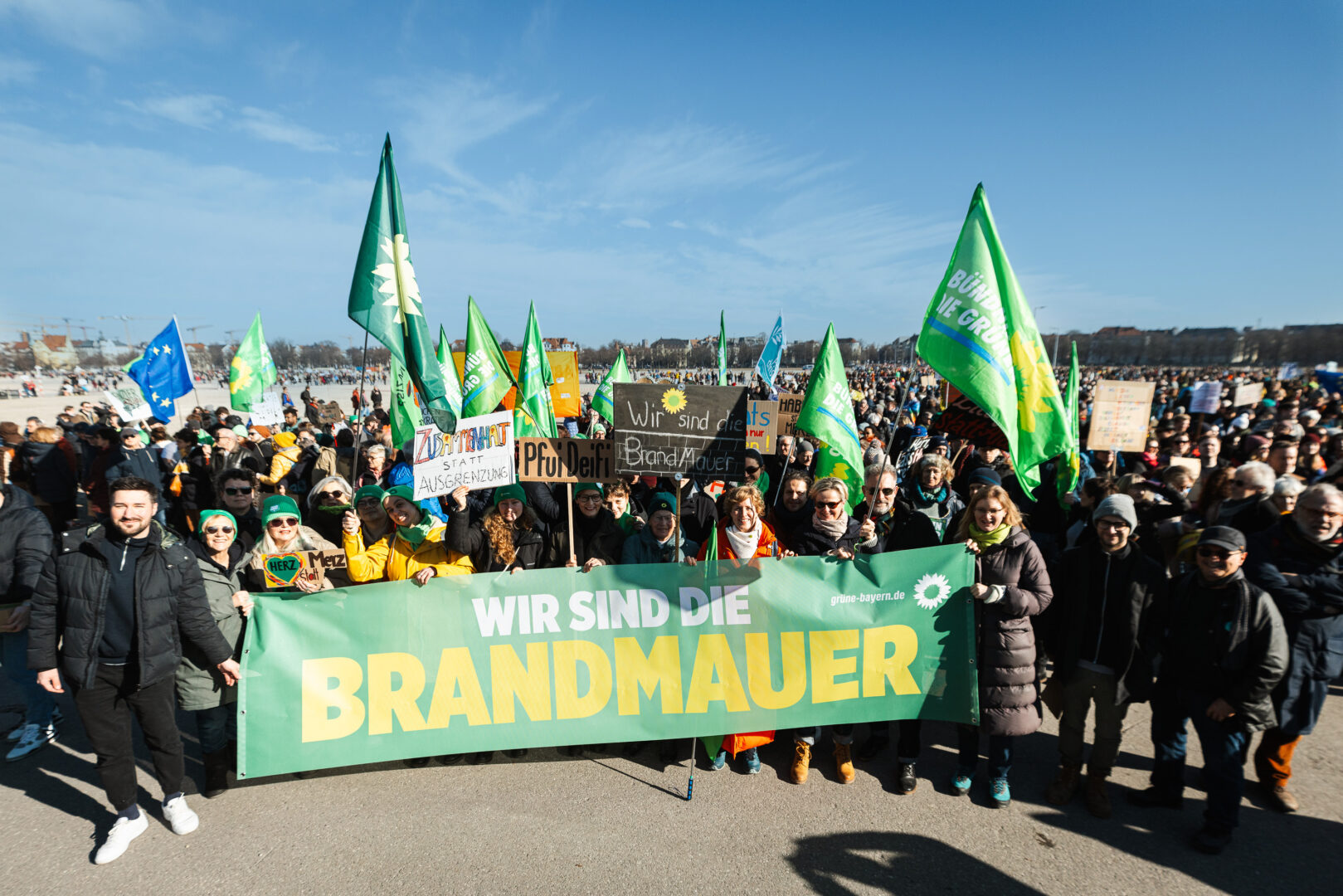 Grüne Gruppe auf der Großdemo für Demokratie am 8.2.2025 auf der Theresienwiese in München mit einem Banner "Wir sind die Brandmauer"